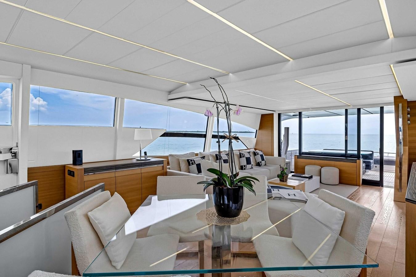 a room with a glass table and couches aboard ARENA Yacht for Sale