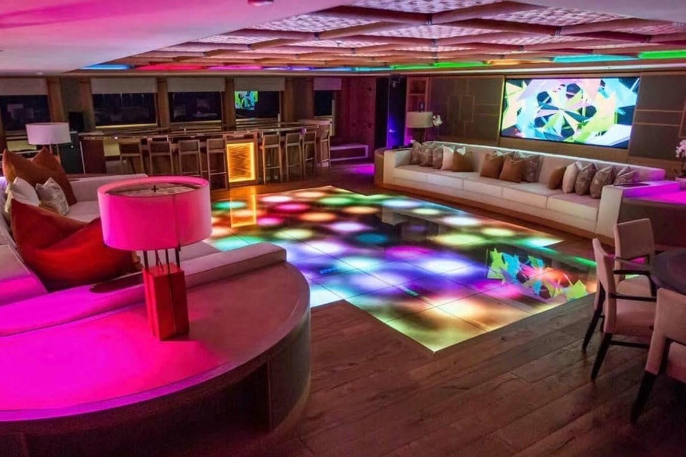 a living room with a large glass table and a large television screen aboard PELORUS Yacht for Sale