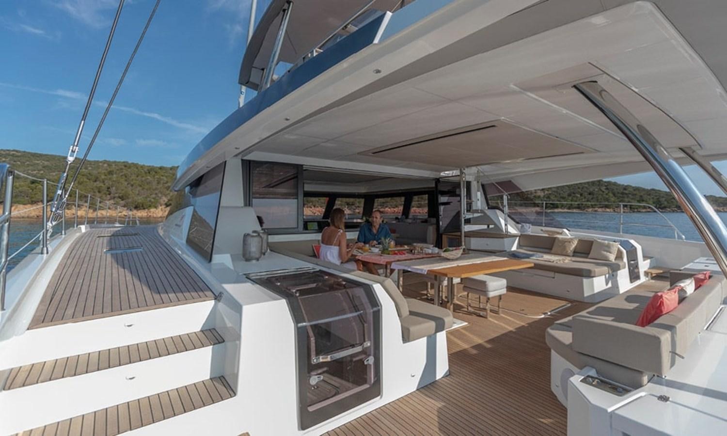 a couple of people sitting at a table on a deck aboard FOUNTAINE PAJOT ALEGRIA 67 Yacht for Sale