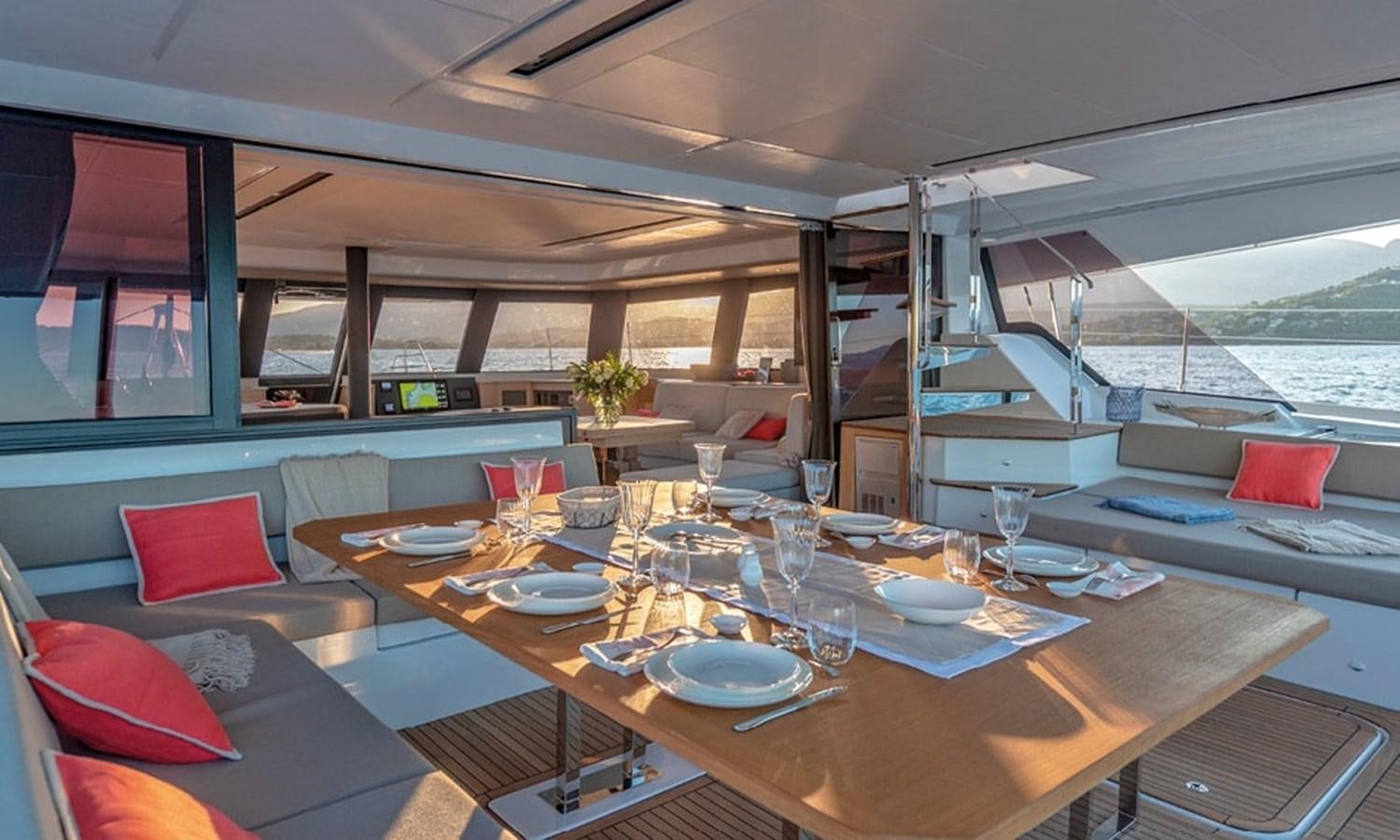 a table with plates and glasses on it aboard FOUNTAINE PAJOT ALEGRIA 67 Yacht for Sale