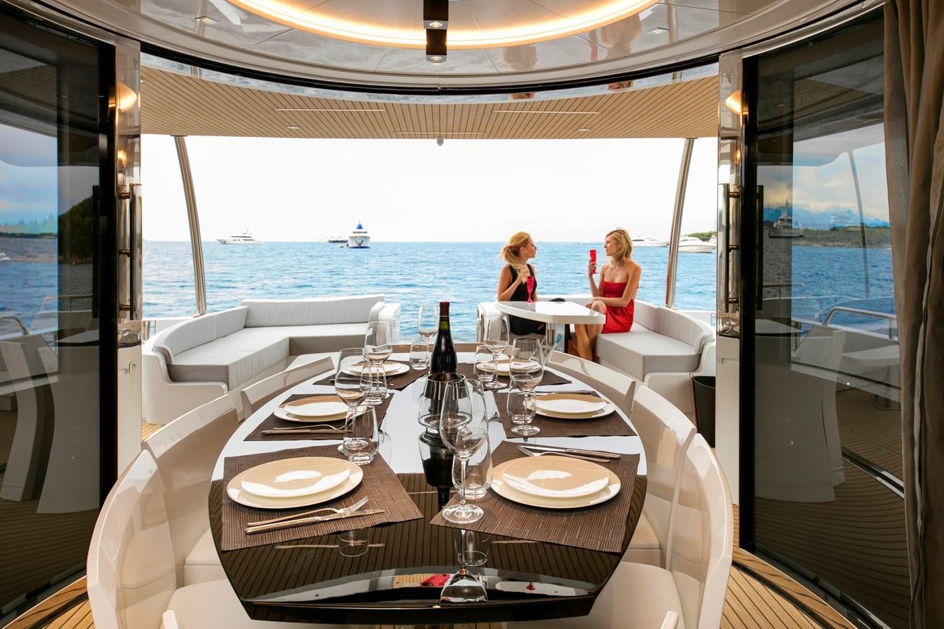 a couple of people sitting at a table with wine glasses and plates on it aboard 2025 CANADOS 808’ MAXIMUS Yacht for Sale