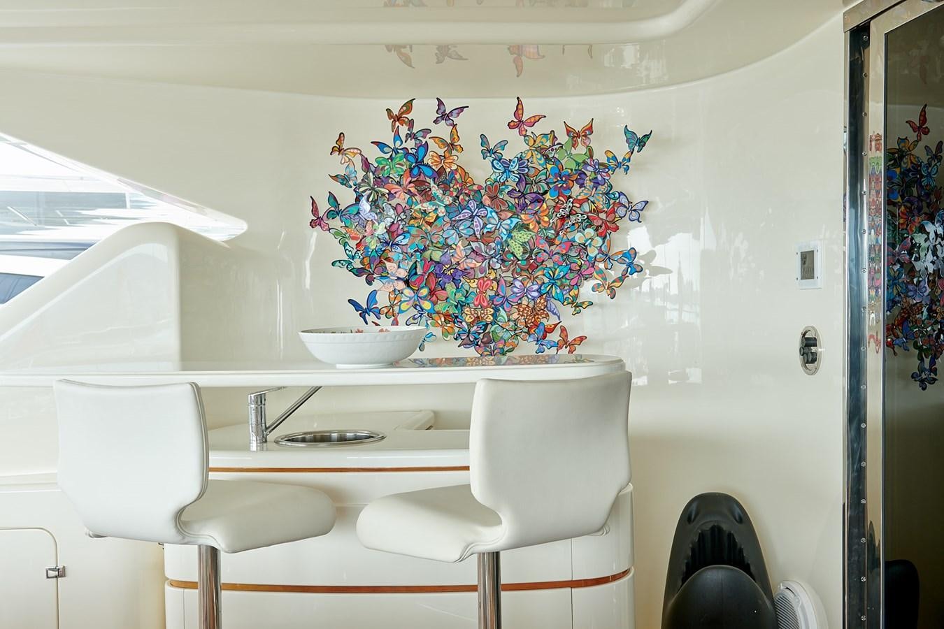 a white chair next to a white table with a bowl of flowers on it aboard BUNKER Yacht for Sale