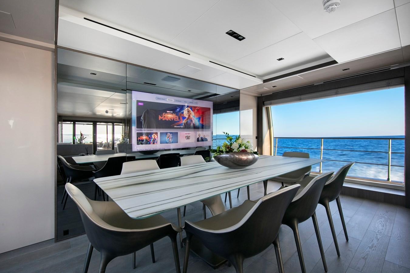 a room with a table and chairs and a tv on the wall aboard CANADOS 122’ CAESAR RPH Yacht for Sale