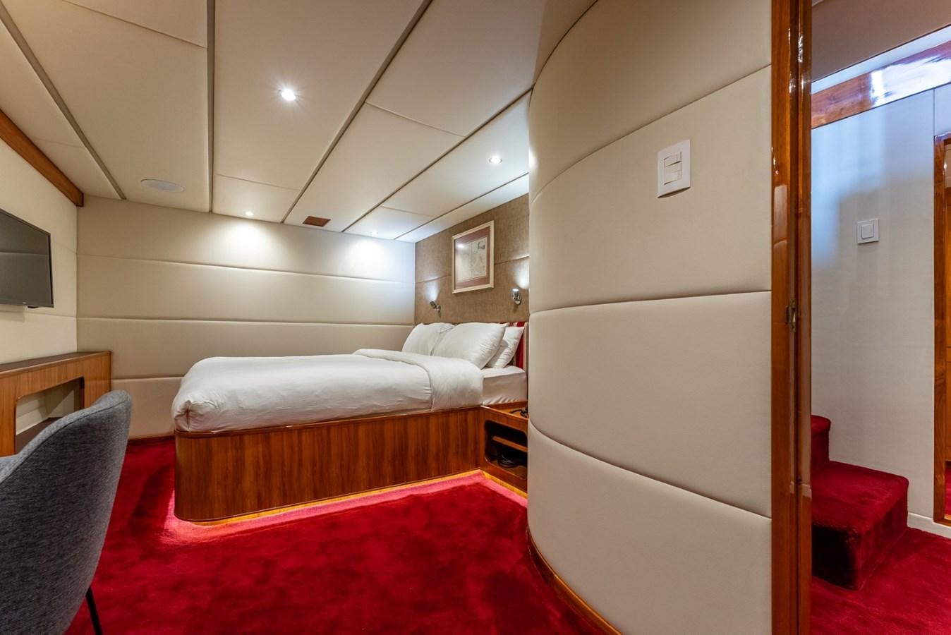 a bedroom with a bed and a red rug aboard HARDHOME Yacht for Sale