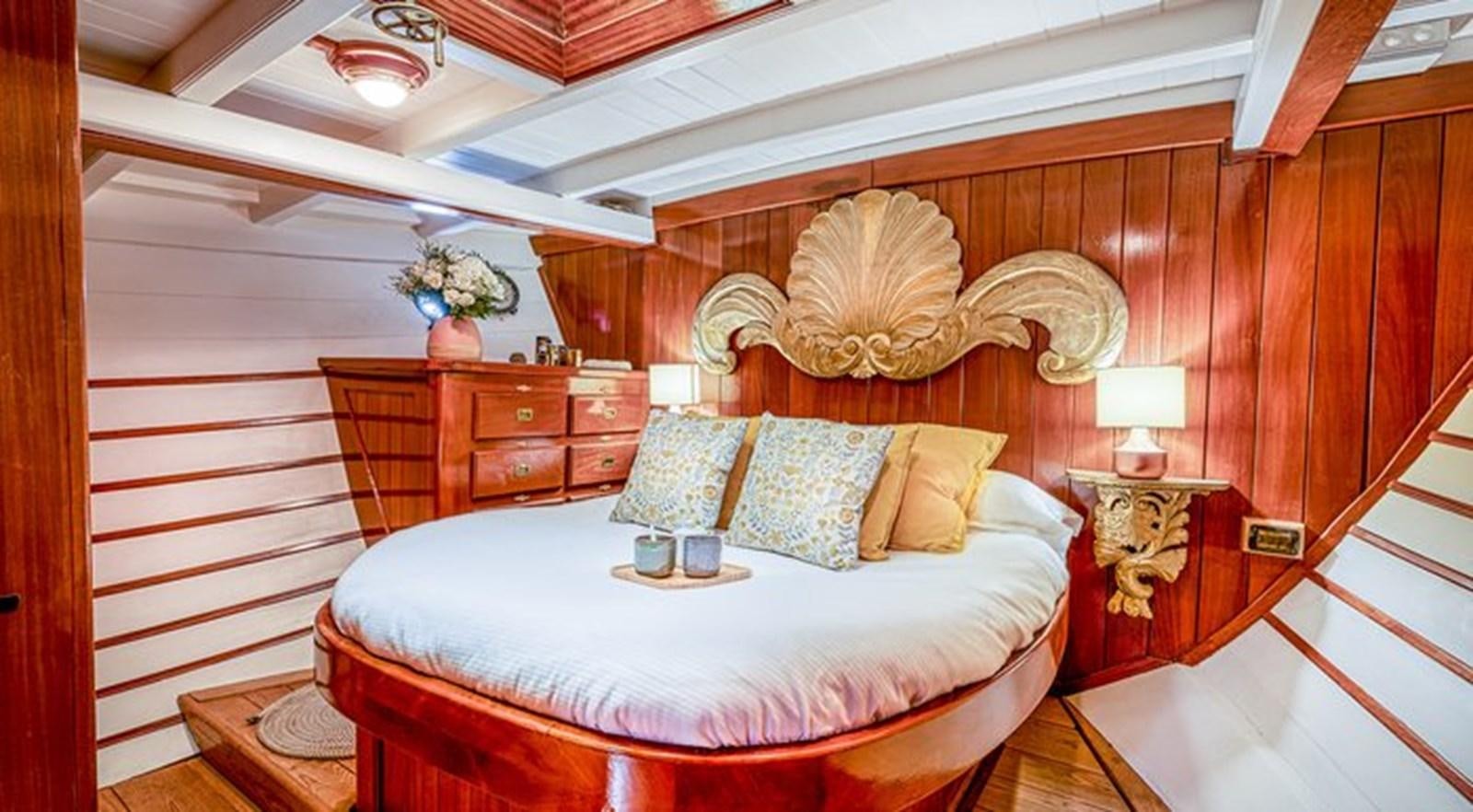a bed with a white sheet and pillows in a room with wood walls aboard O'REMINGTON Yacht for Sale