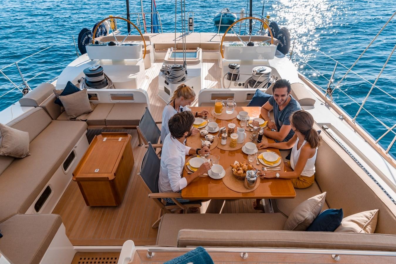 a group of people sitting around a table on a boat aboard GRAND BLEU VINTAGE Yacht for Sale