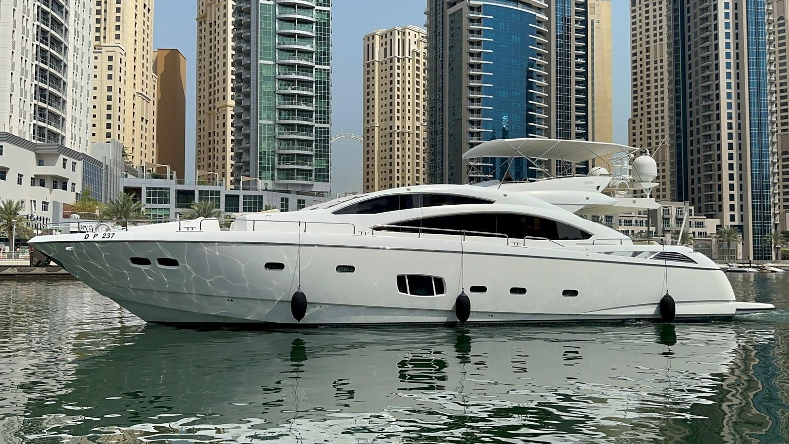 a white yacht in a body of water with tall buildings in the background aboard MANIA Yacht for Sale