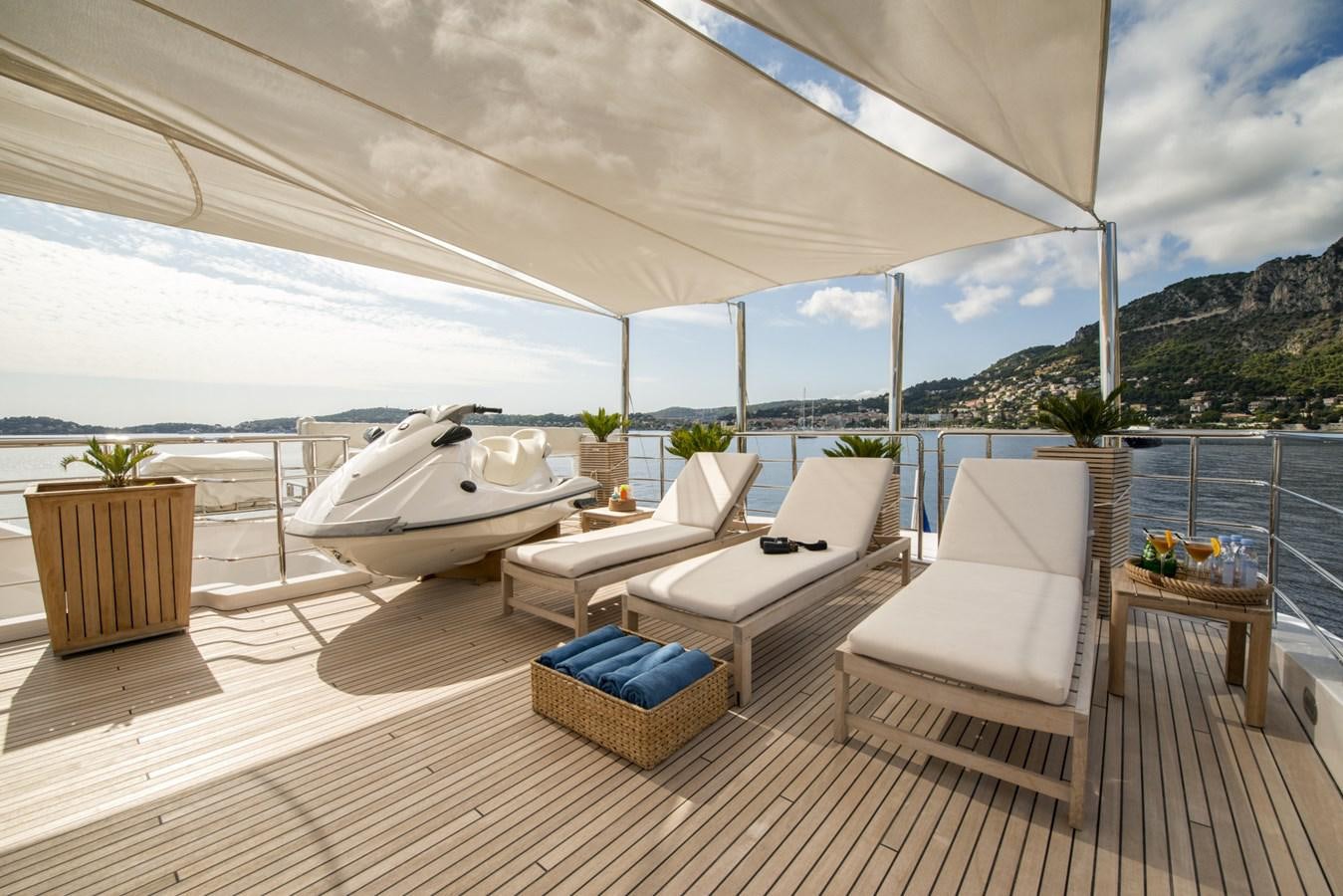 a lounge area with a large white lounge chair and a large body of water aboard TIAMAT Yacht for Sale