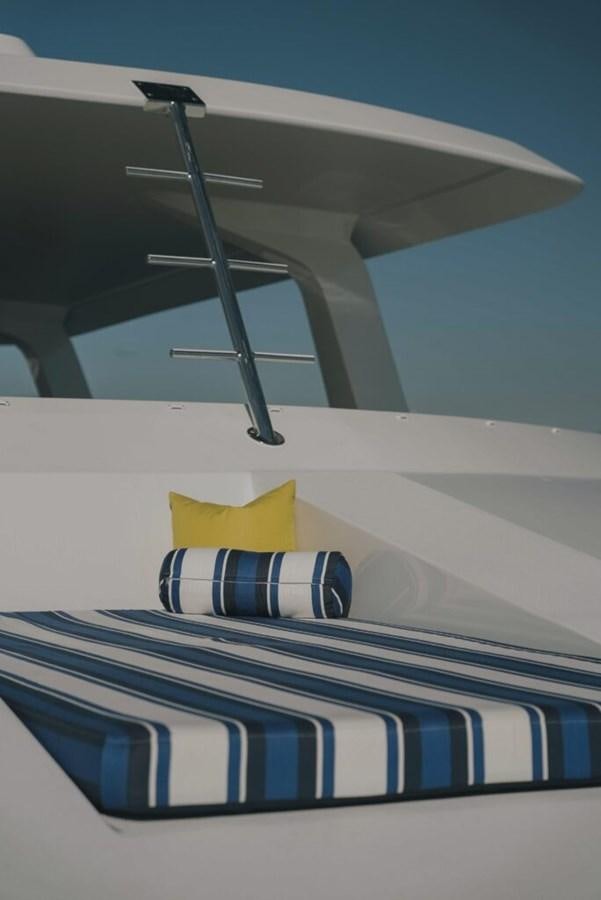 a white and blue striped bed with a blue and yellow pillow aboard SALTY Yacht for Sale