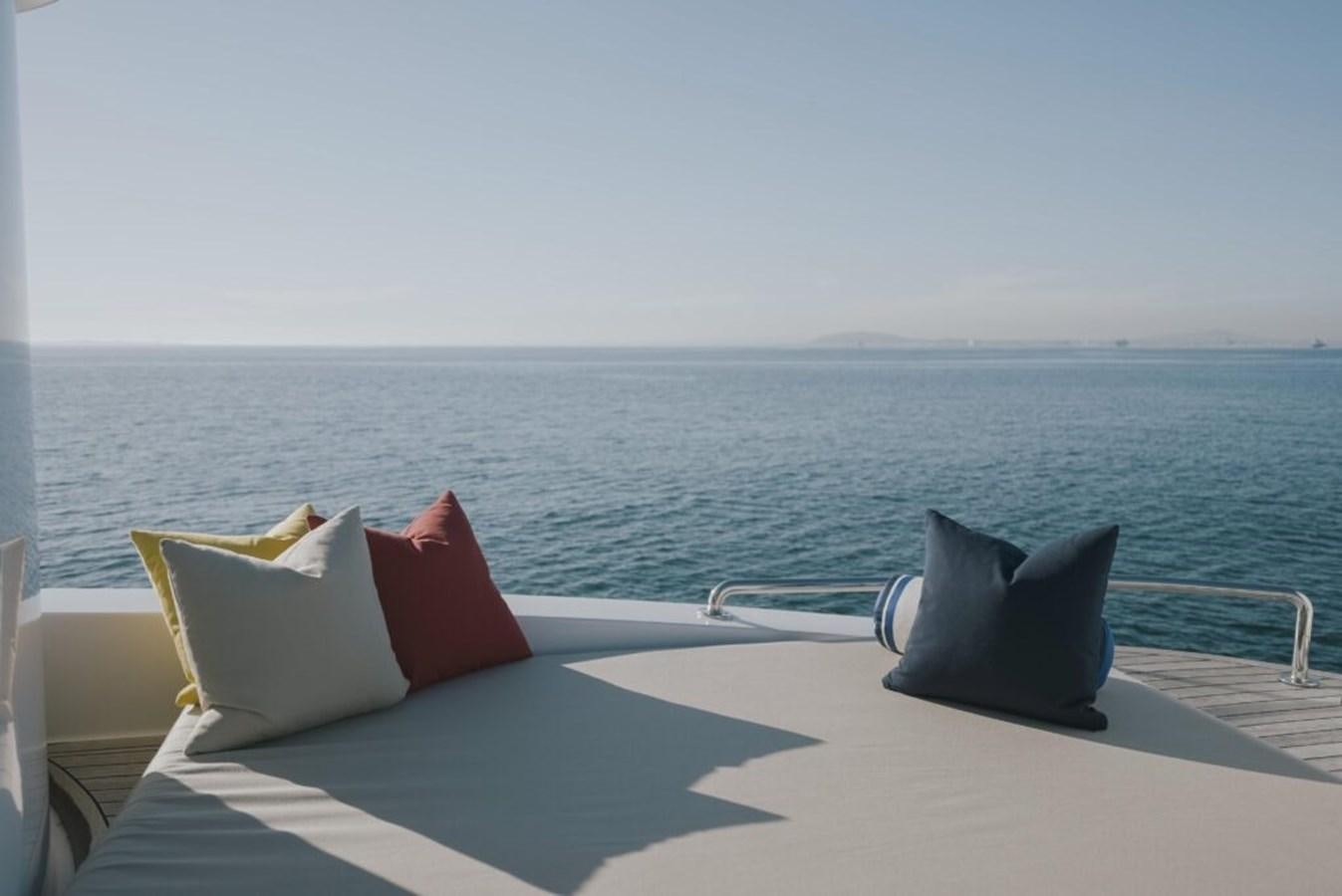 a deck with pillows and a chair on it by the water aboard SALTY Yacht for Sale