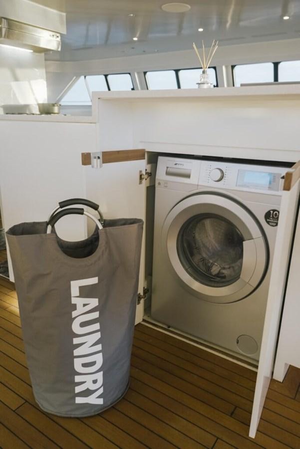 a laundry basket next to a washing machine aboard SALTY Yacht for Sale