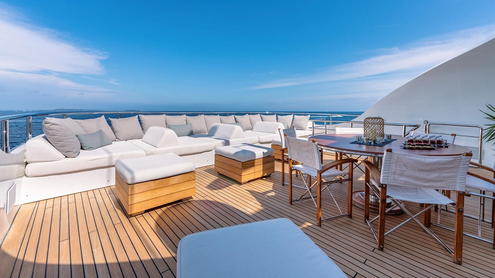 a large lounge area with a large white sofa and a table and chairs aboard LOTUS Yacht for Sale
