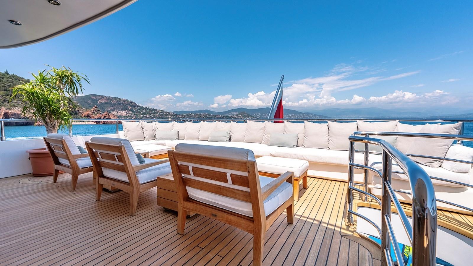 a deck with chairs and a body of water in the background aboard LOTUS Yacht for Sale