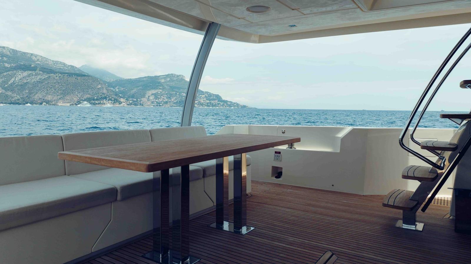 a deck with a view of the ocean and mountains aboard FEU D'OR Yacht for Sale