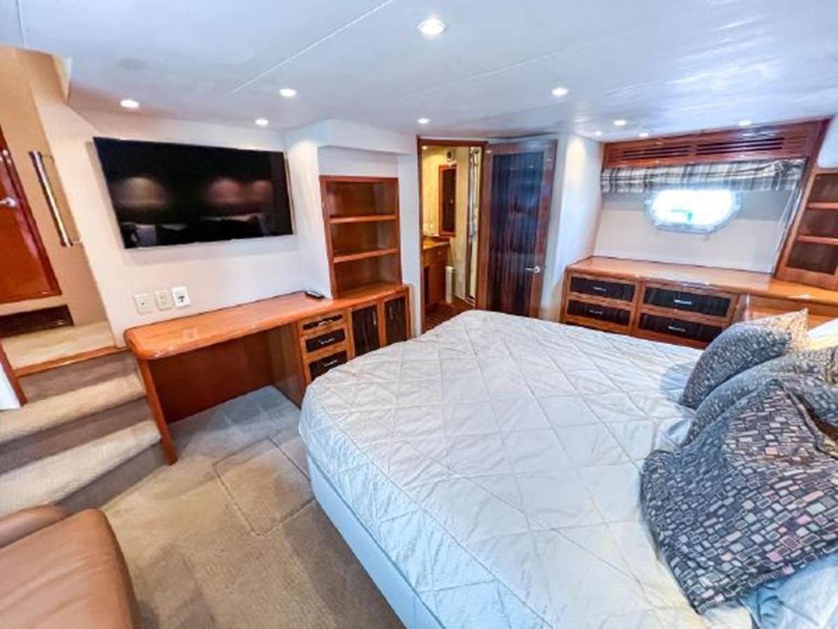 a bedroom with a bed and a television aboard 2007 68 HATTERAS CONVERTIBLE Yacht for Sale