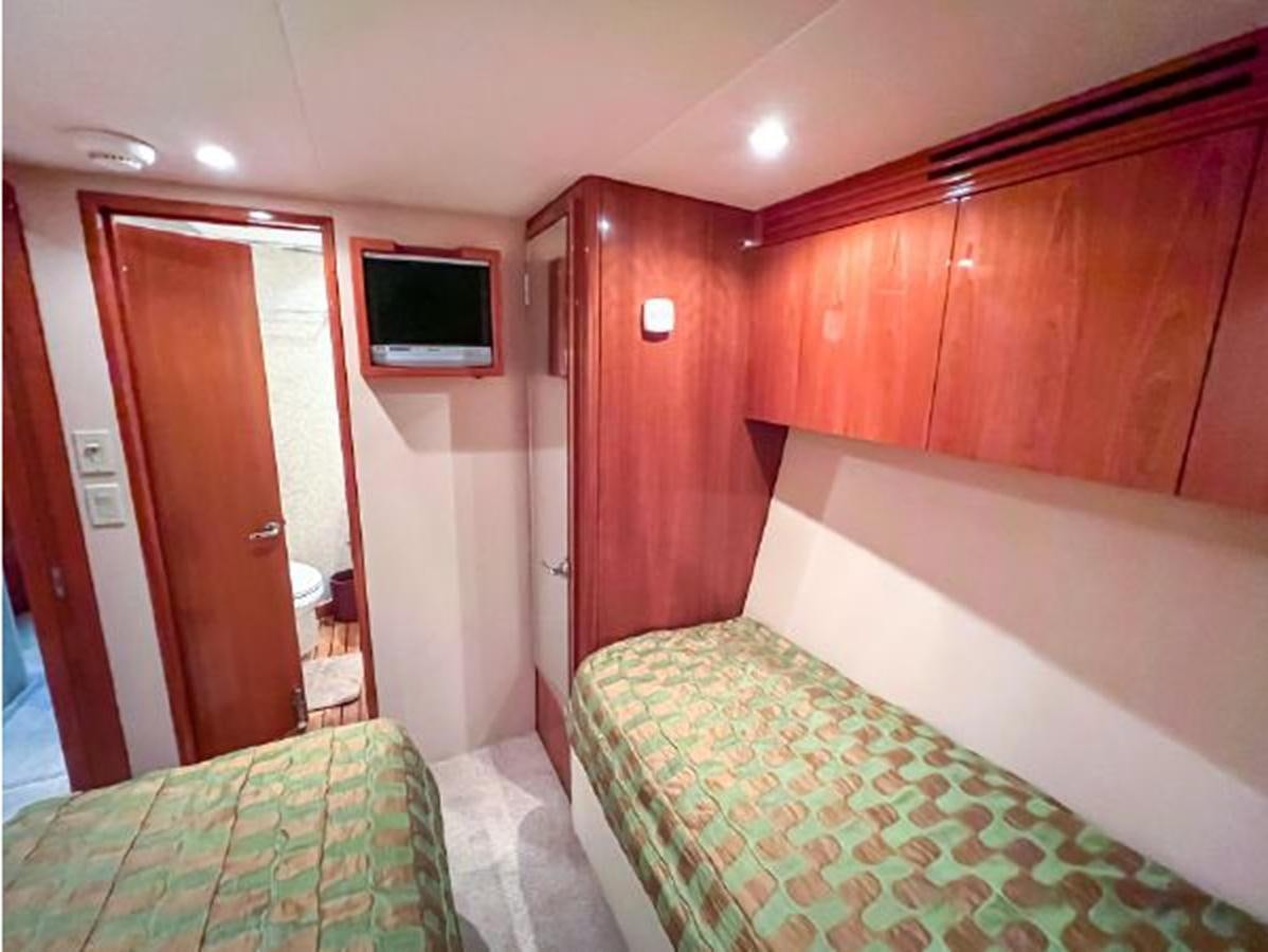 a bedroom with a bed and a television aboard 2007 68 HATTERAS CONVERTIBLE Yacht for Sale
