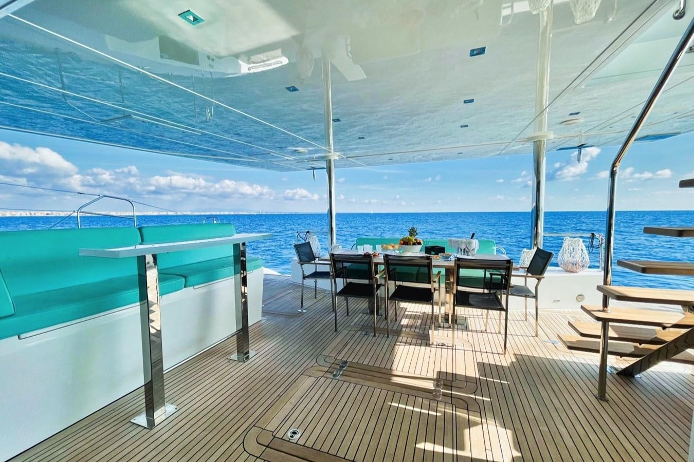 a deck with chairs and tables on it by the water aboard ALKIMIA Yacht for Sale