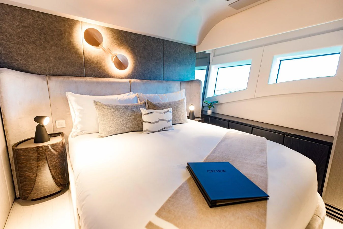 a bed with a blue book on it aboard OFFLINE Yacht for Sale