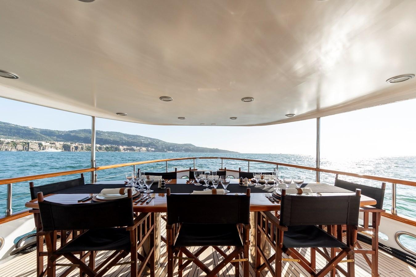 a table and chairs on a deck overlooking a large body of water aboard SOUNION II Yacht for Sale