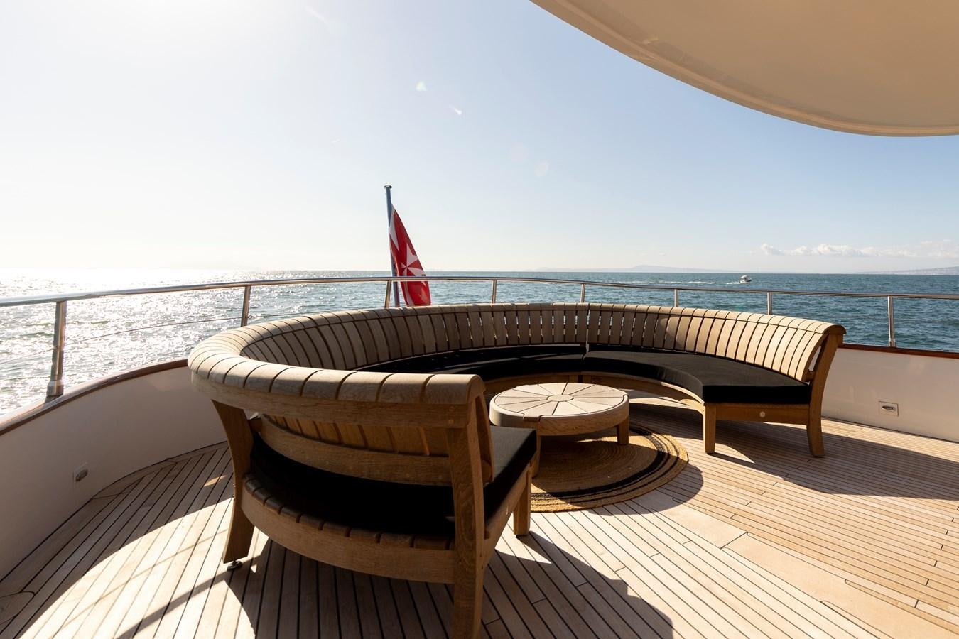 a table and chairs on a deck overlooking a body of water aboard SOUNION II Yacht for Sale