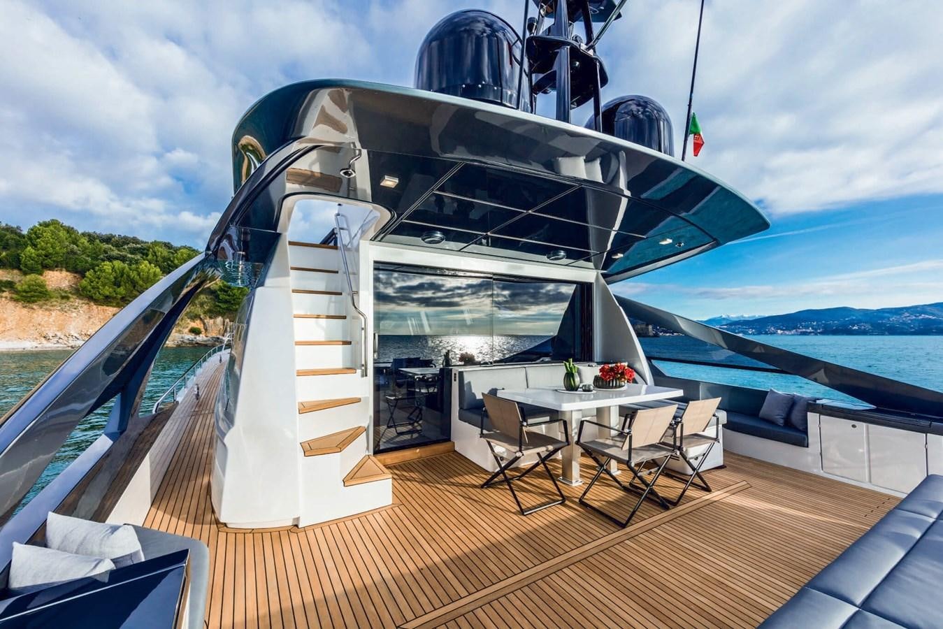 a deck with a table and chairs on it aboard EL MACANN Yacht for Sale