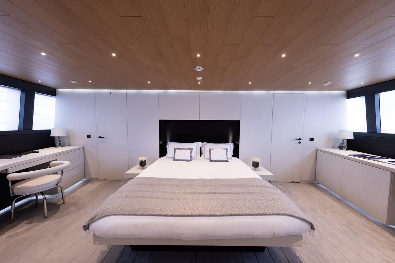 a large white bedroom with a large bed and a desk aboard OCEAN PEARL - FRACTIONAL OWNERSHIP VESSEL Yacht for Sale