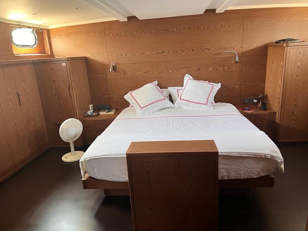 a bed with a white sheet and pink pillows aboard AYO Yacht for Sale