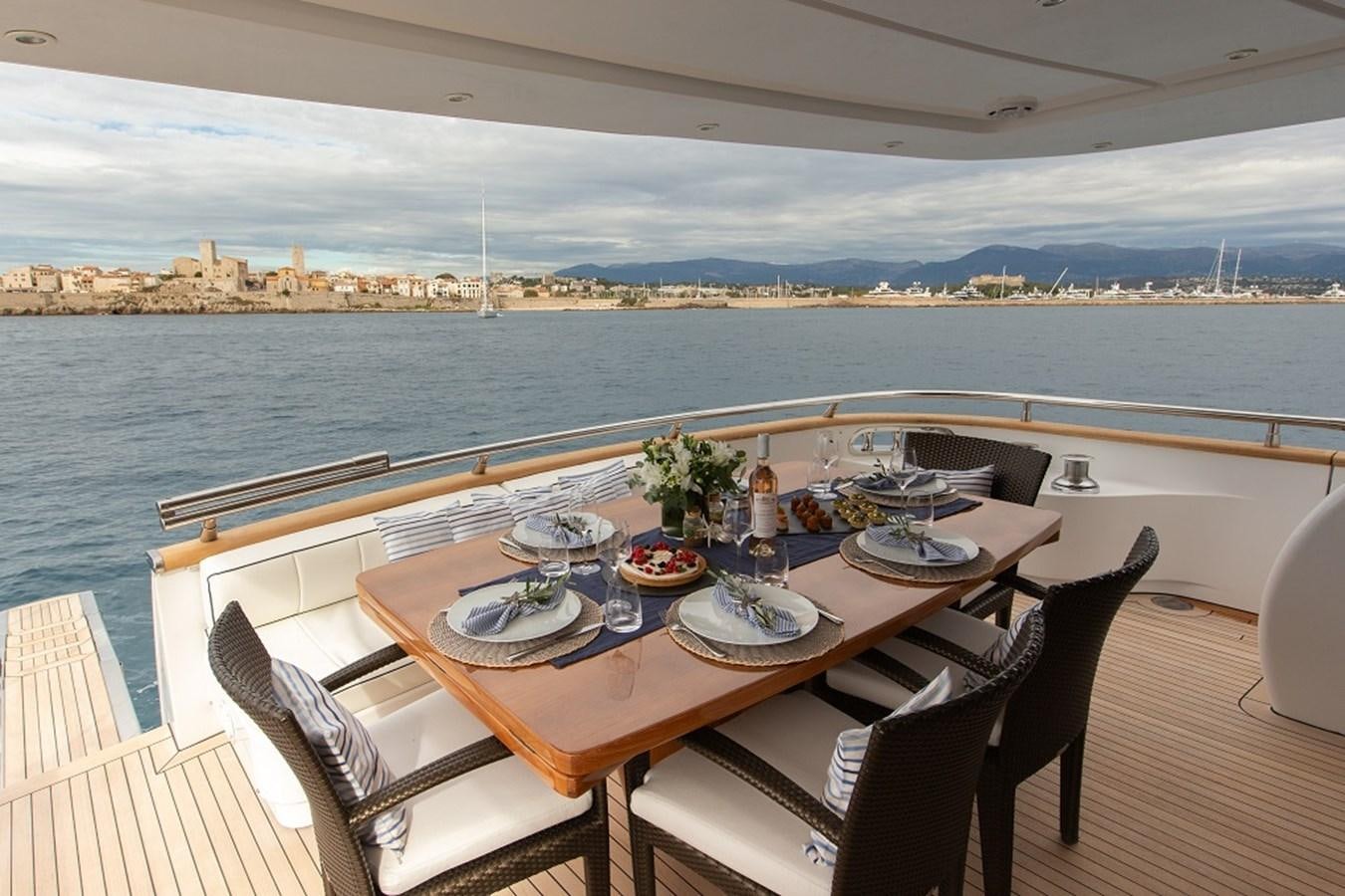 a table with plates and chairs on a deck overlooking a body of water aboard MEME Yacht for Sale