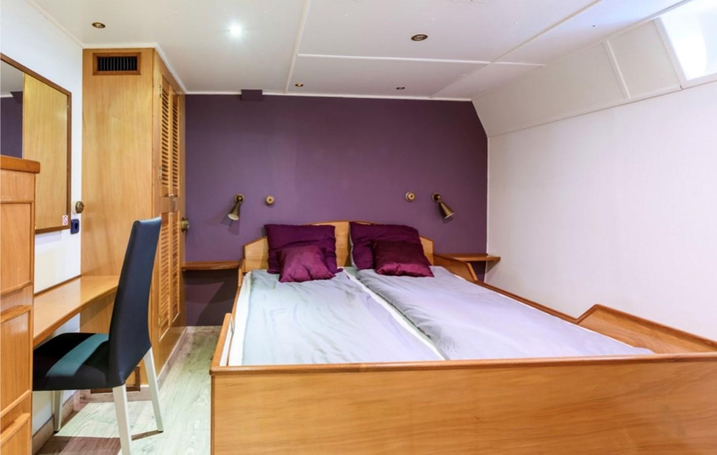 a bedroom with a bed and a chair aboard FAMILY Yacht for Sale