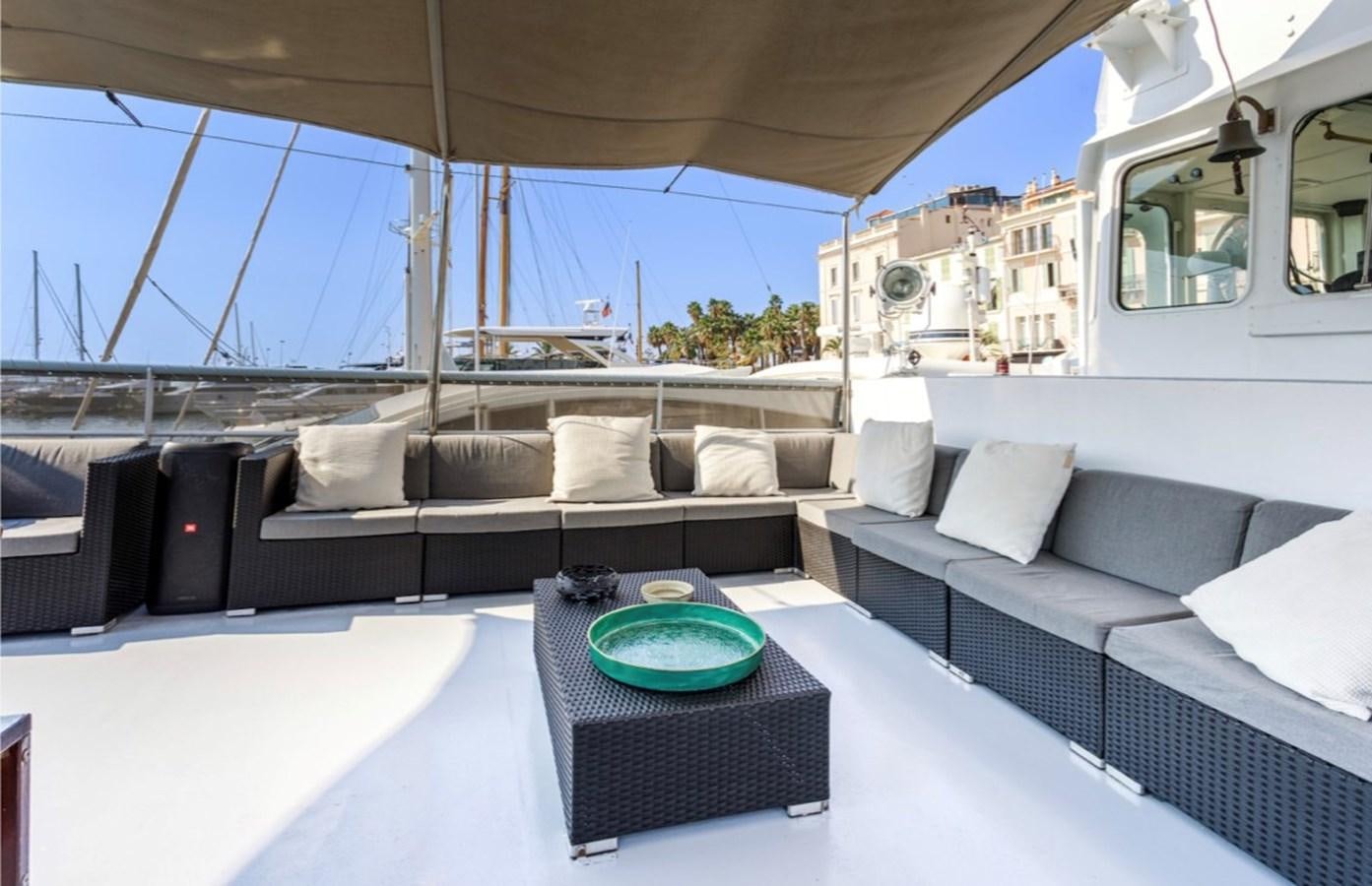 a large white boat with a round table and a black table on a boat aboard FAMILY Yacht for Sale
