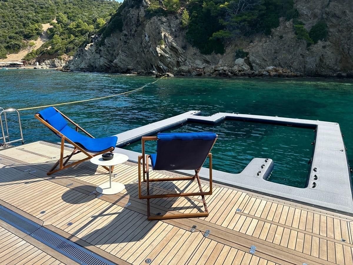 a deck with chairs and a table on it by a body of water aboard NG Yacht for Sale
