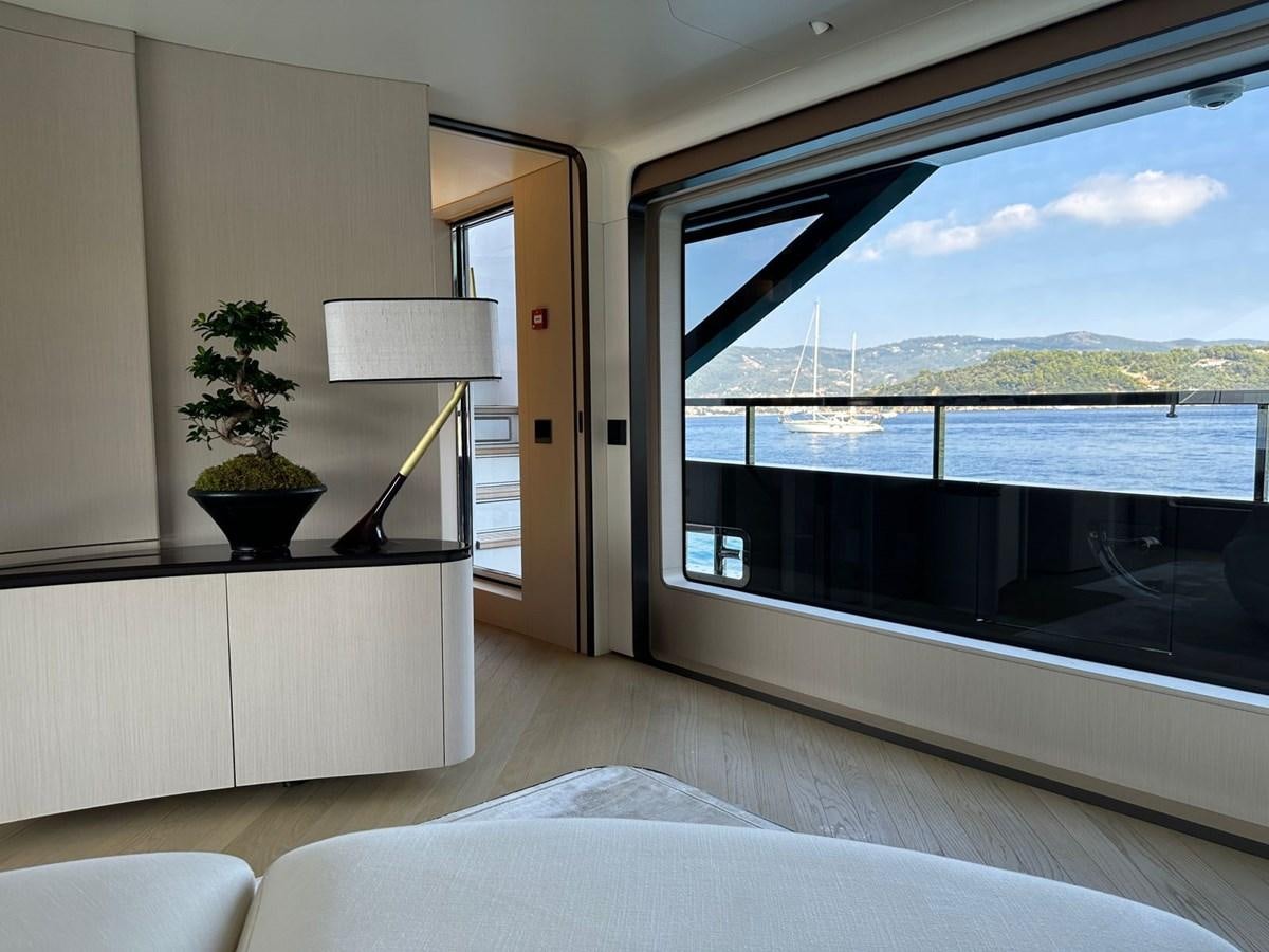 a room with a large window and a bed and a plant on the window sill aboard NG Yacht for Sale