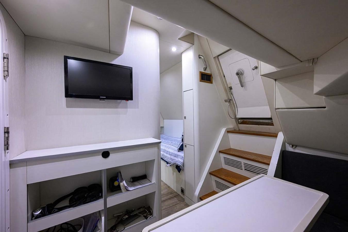 a room with a tv and a shelf with books aboard XHALE Yacht for Sale