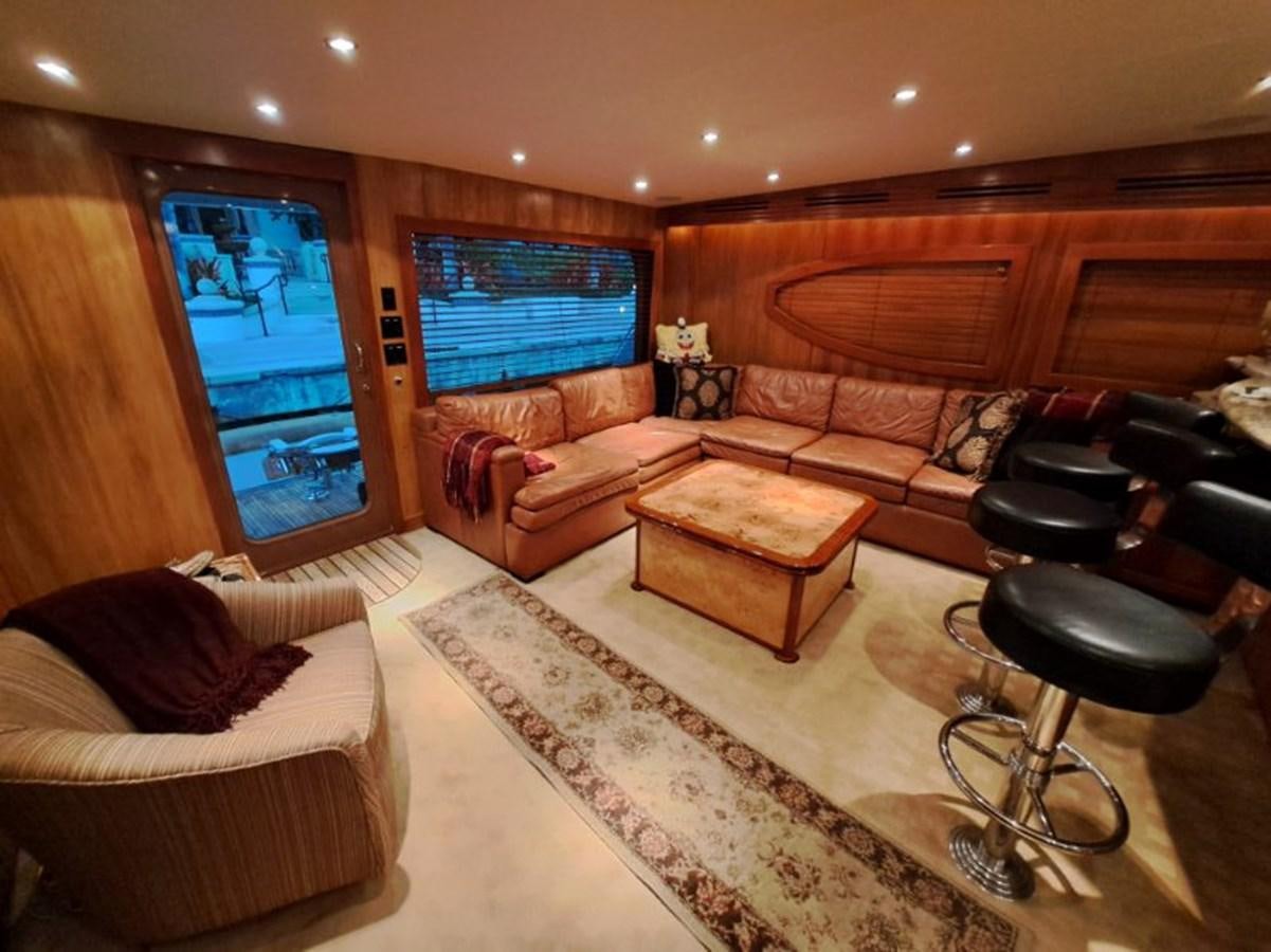 a living room with leather couches and a large window aboard CLAIRE TOO Yacht for Sale