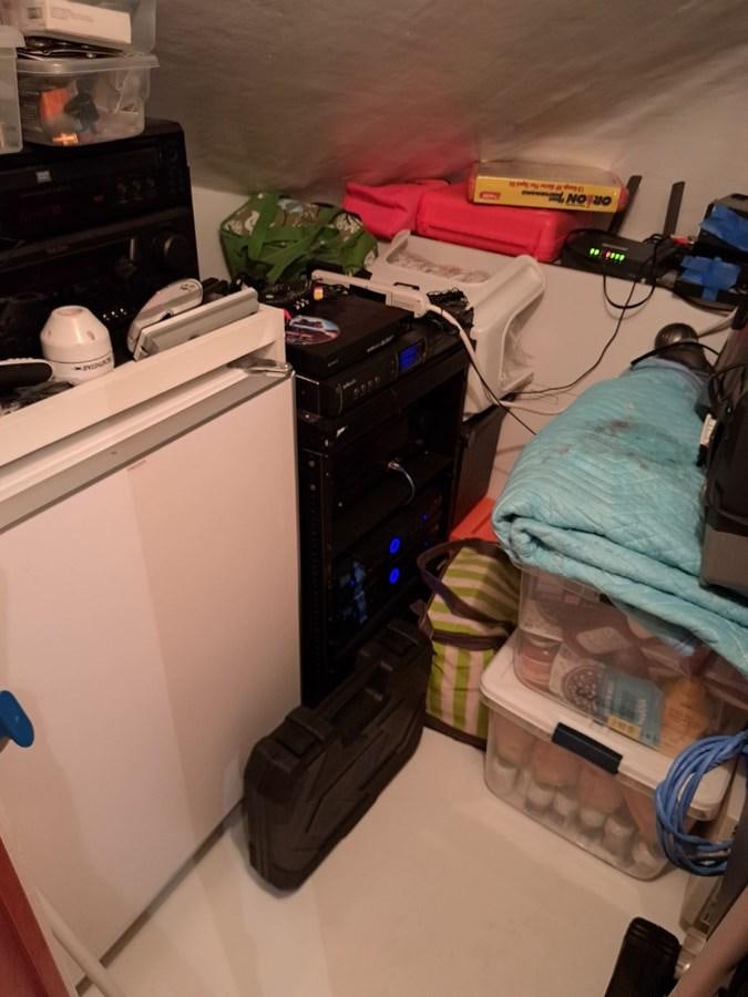 a room with a bed and a desk with a computer and other items aboard CLAIRE TOO Yacht for Sale