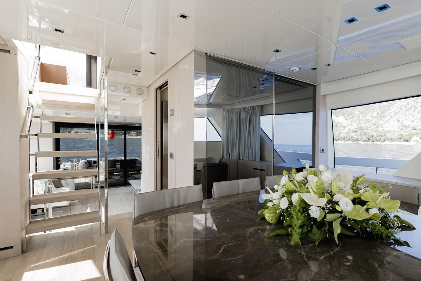 a room with a large glass window and a table with chairs and a large white shelf with white aboard RADKAT Yacht for Sale