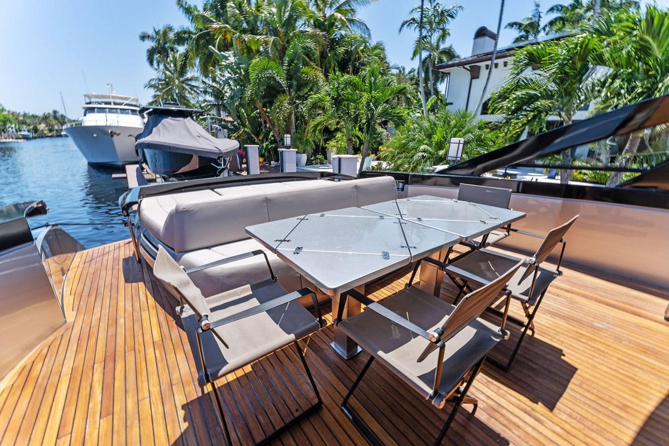 a deck with a table and chairs on it aboard LIQUID Yacht for Sale