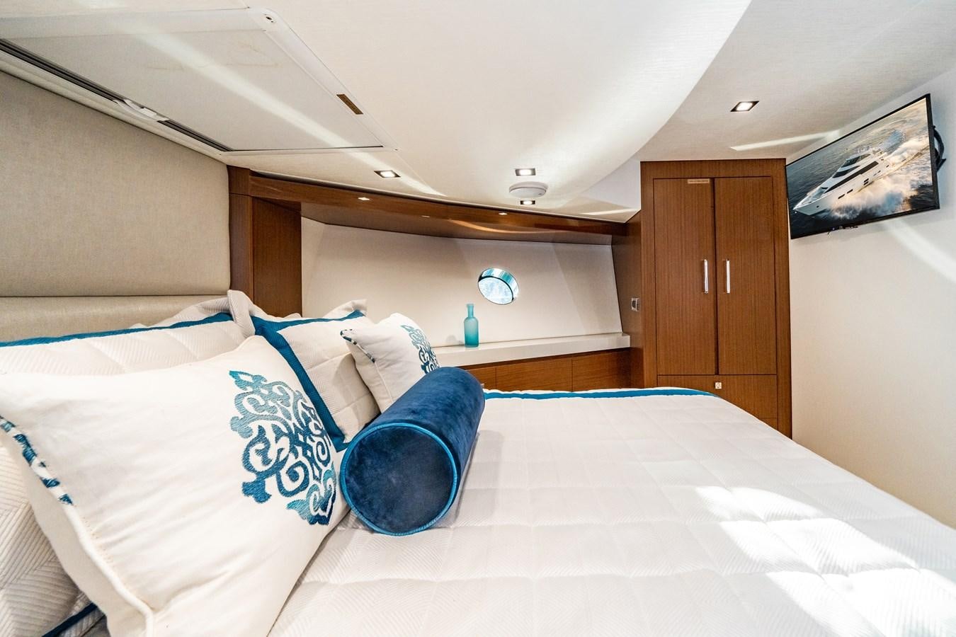 a bed with blue pillows aboard 2017 HATTERAS M75 K SEA Yacht for Sale