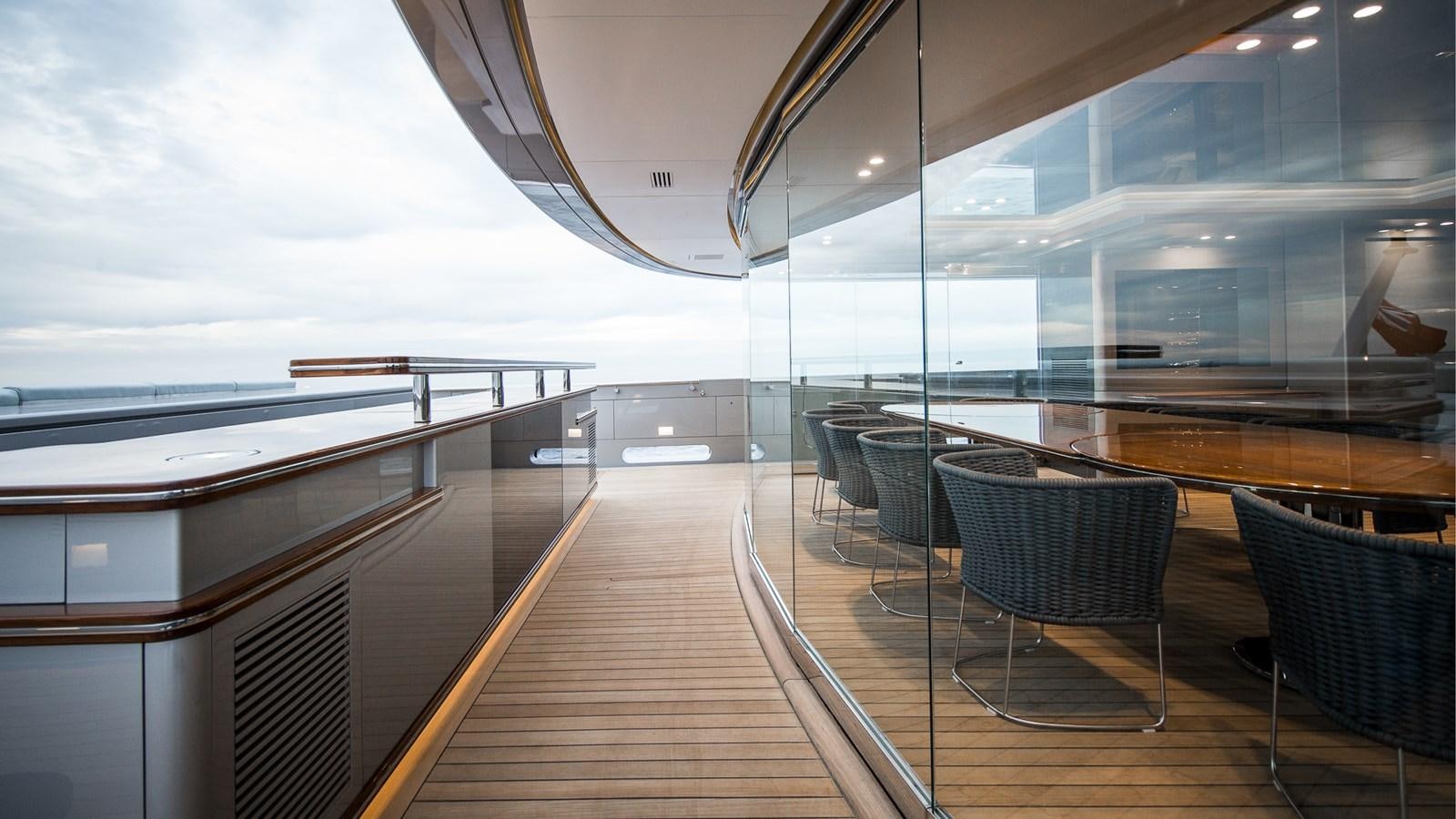 a wooden deck with chairs and a large window aboard SILVER EDGE Yacht for Sale