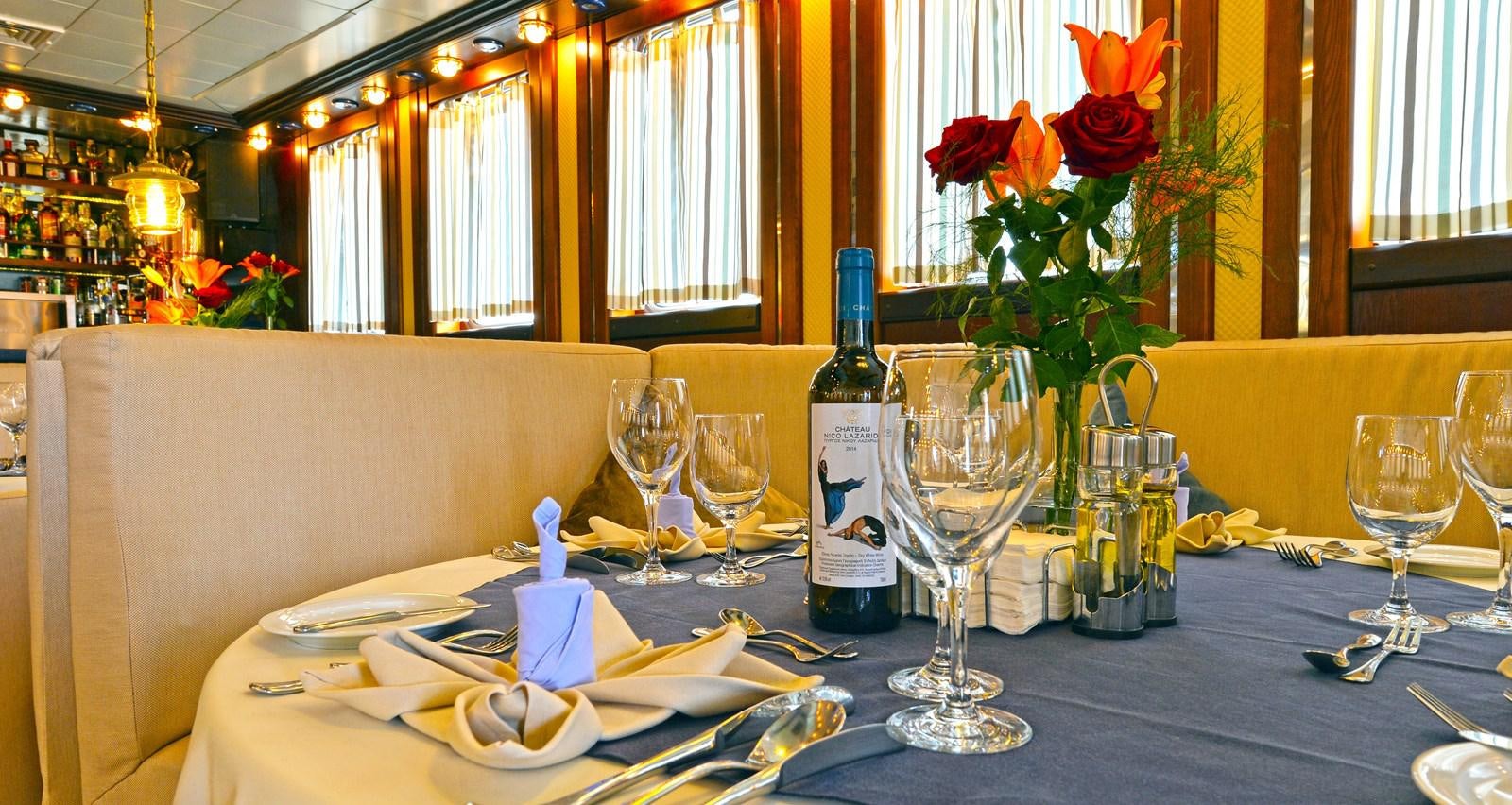 a table with wine glasses and plates aboard RUNNING ON WAVES Yacht for Sale