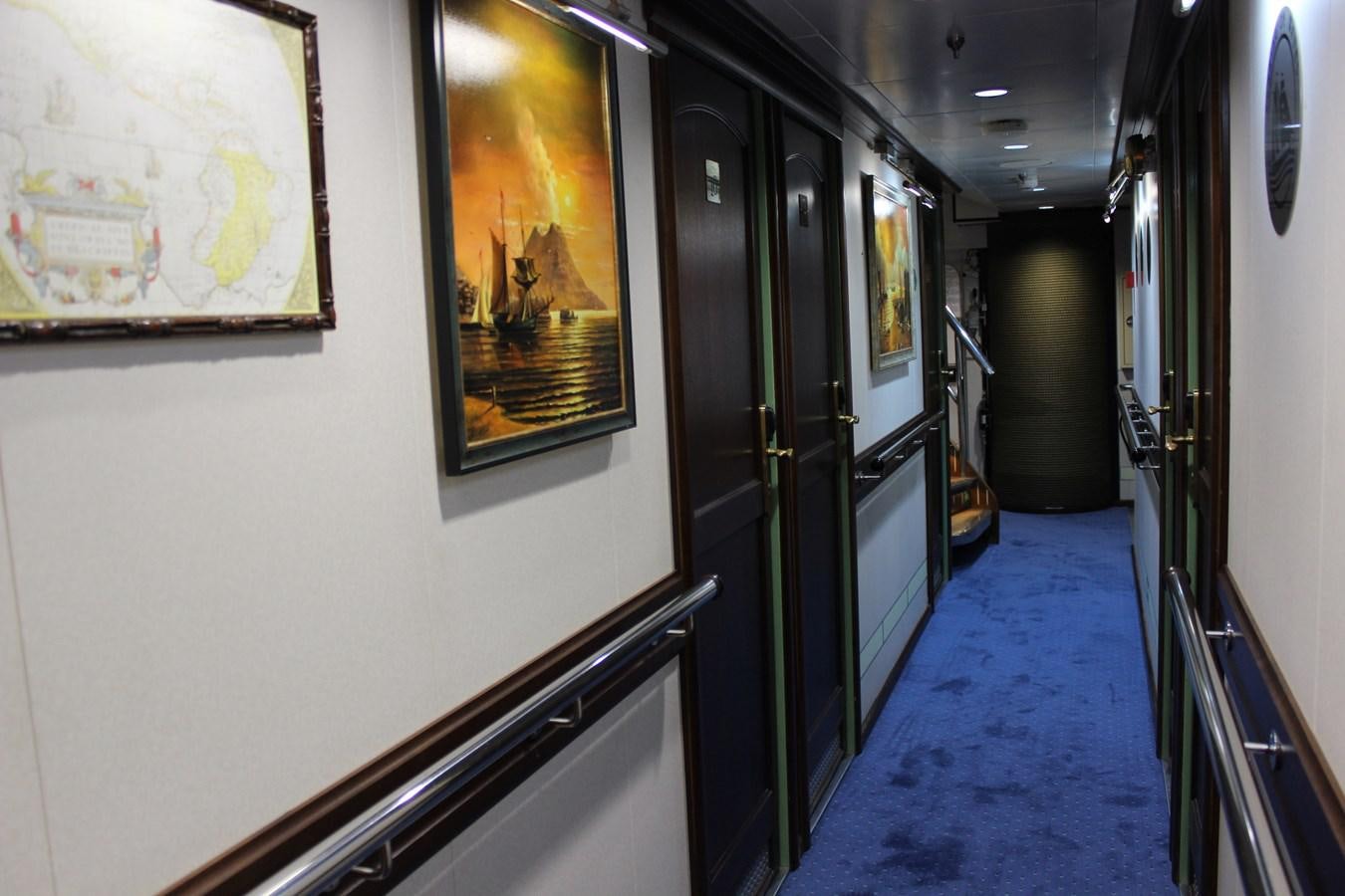 a hallway with blue carpet and a painting on the wall aboard RUNNING ON WAVES Yacht for Sale