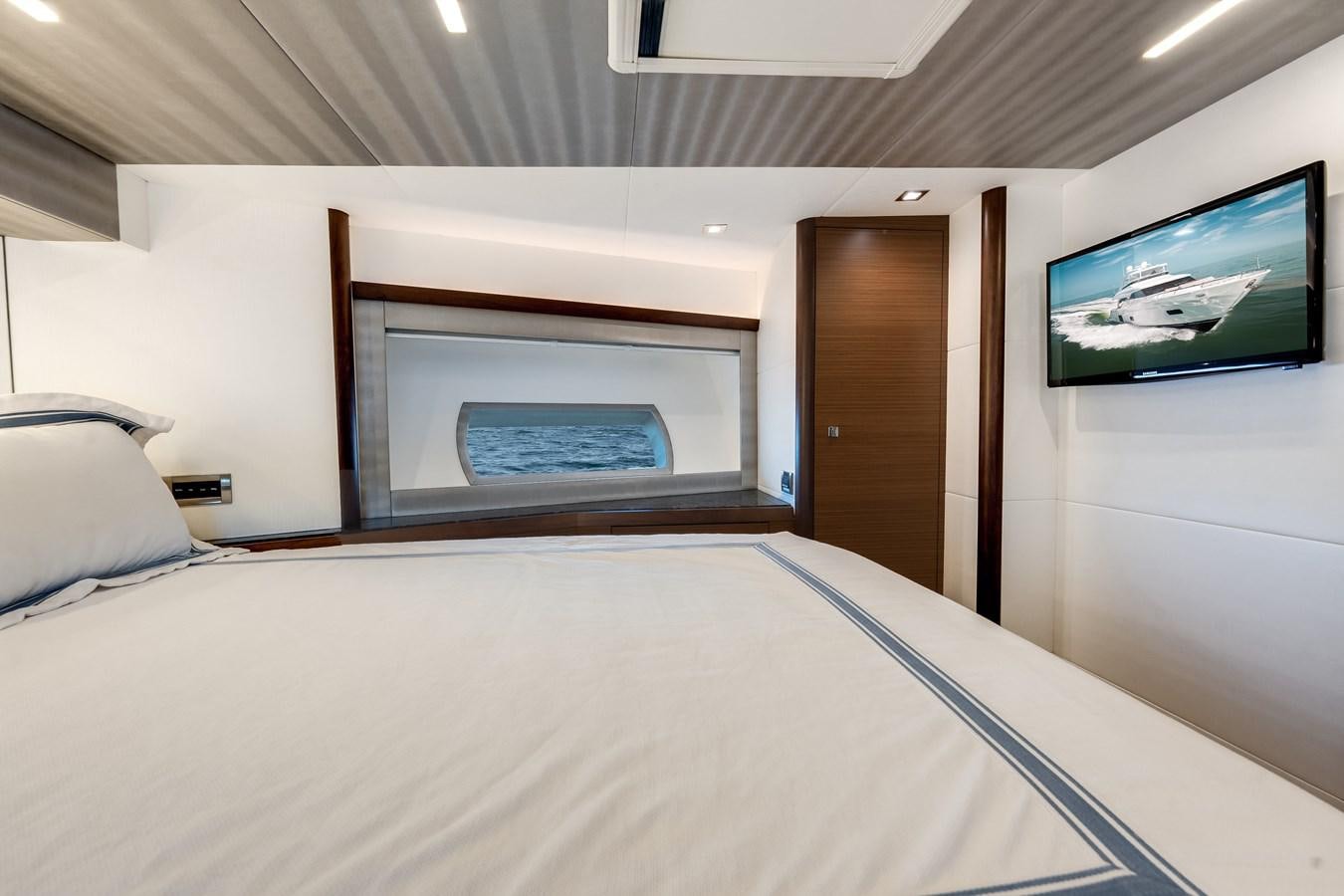 a bed with a white sheet and a television on the wall aboard 2018 OCEAN ALEXANDER 70E TIRESUM Yacht for Sale