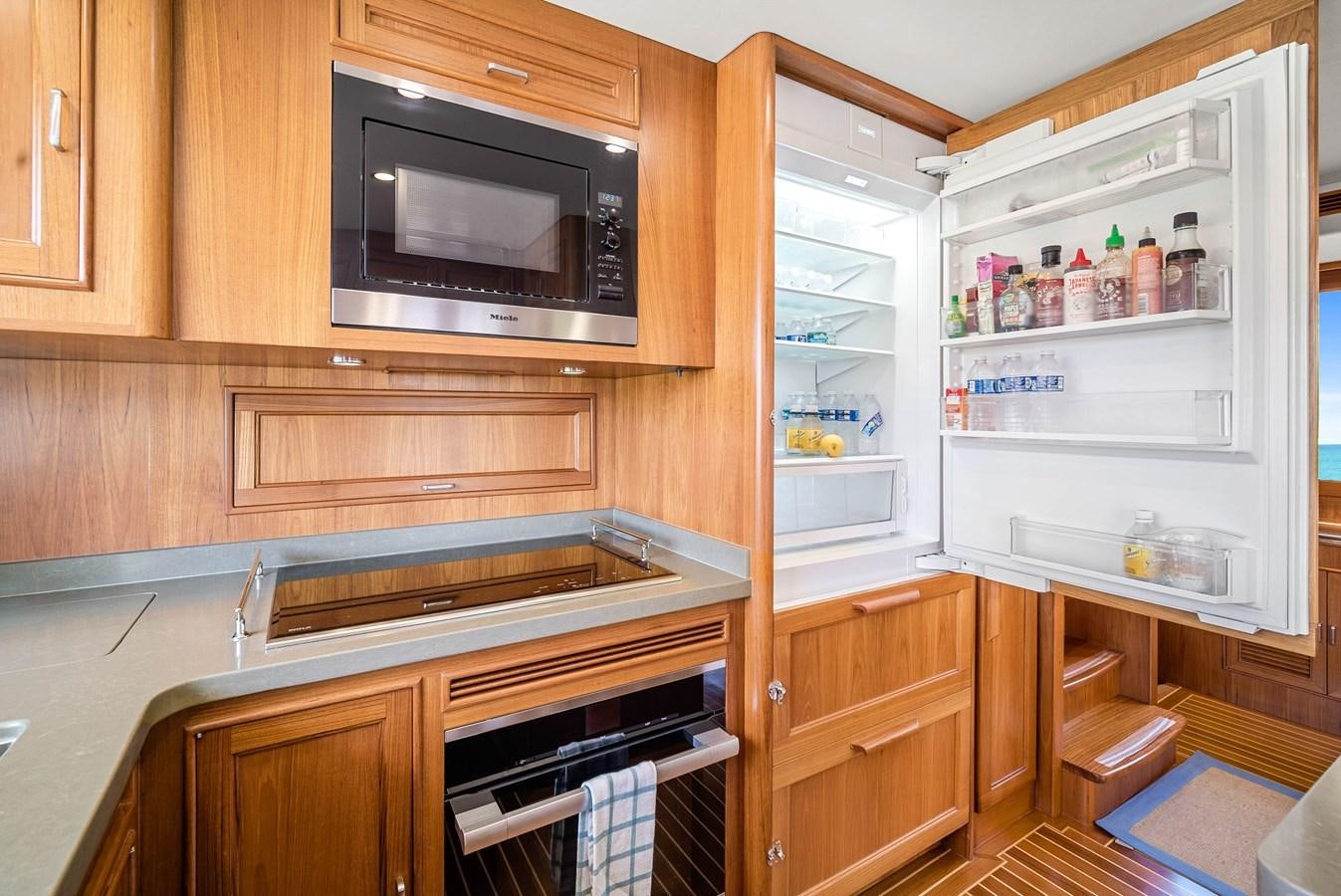 a kitchen with a refrigerator and microwave aboard FLEMING 78 - CLASSIC FLYBRIDGE Yacht for Sale