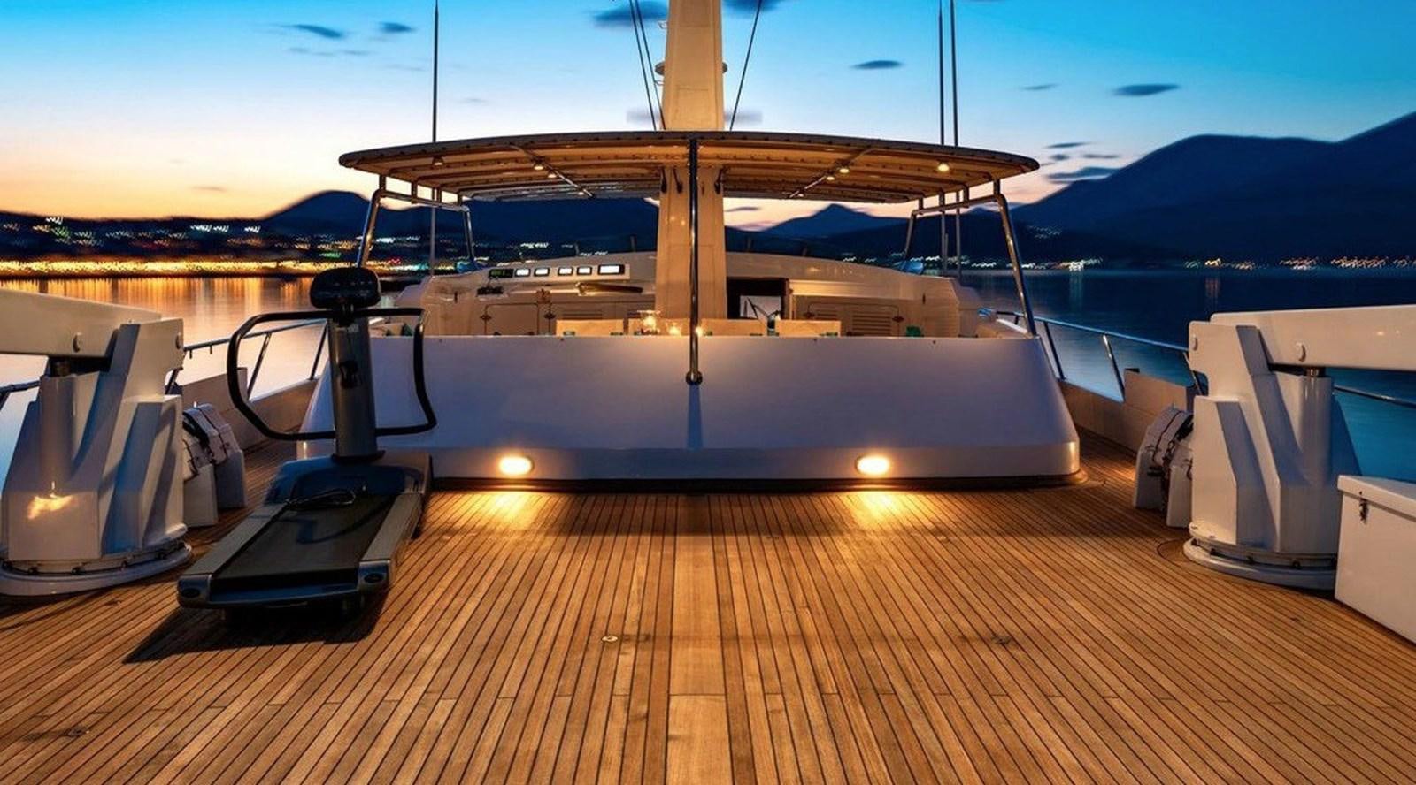 a deck with a large boat on it and a dock with a view of the water and mountains aboard NIGHTFLOWER Yacht for Sale