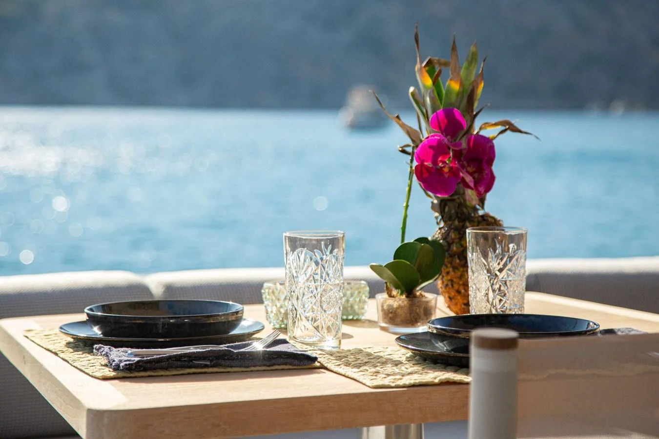 a table with a flower in a vase and a plate of food aboard 2020 BLUEGAME BGX70 #02 Yacht for Sale