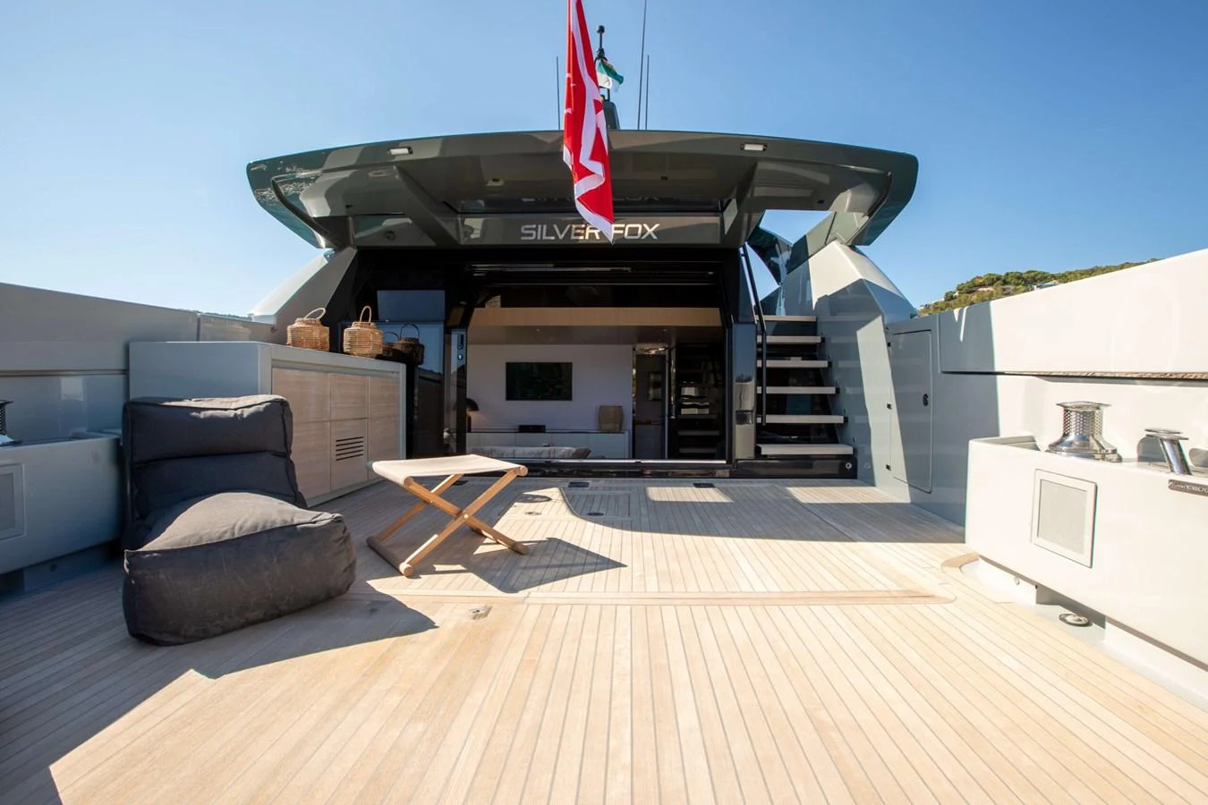 a large black and white building with a wood deck and a large black grill on a sunny day aboard 2020 BLUEGAME BGX70 #02 Yacht for Sale