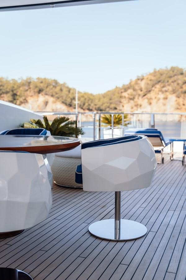 a table with chairs and a view of a city aboard ALULIM Yacht for Sale