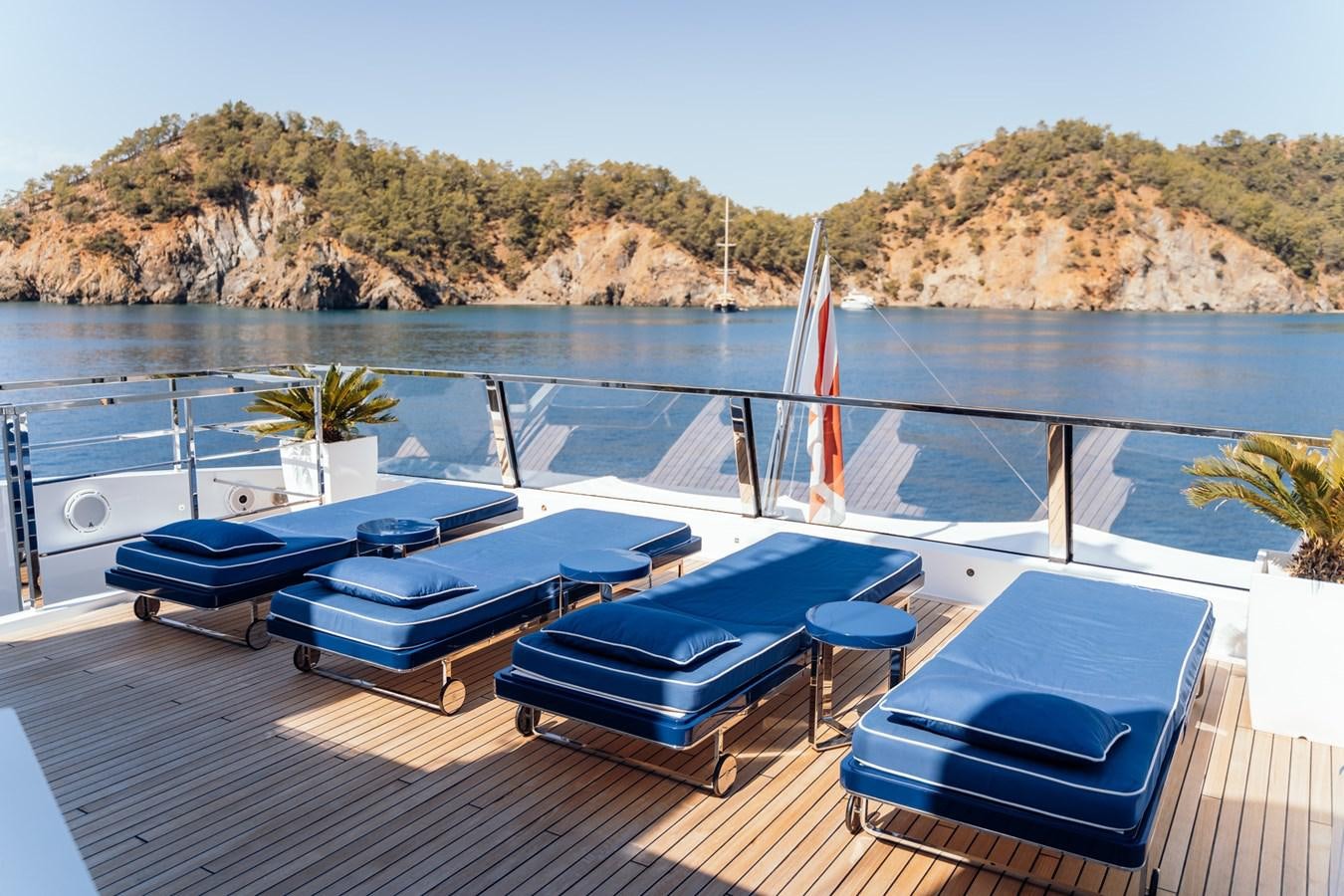 a deck with a pool and a deck with chairs and trees in the background aboard ALULIM Yacht for Sale