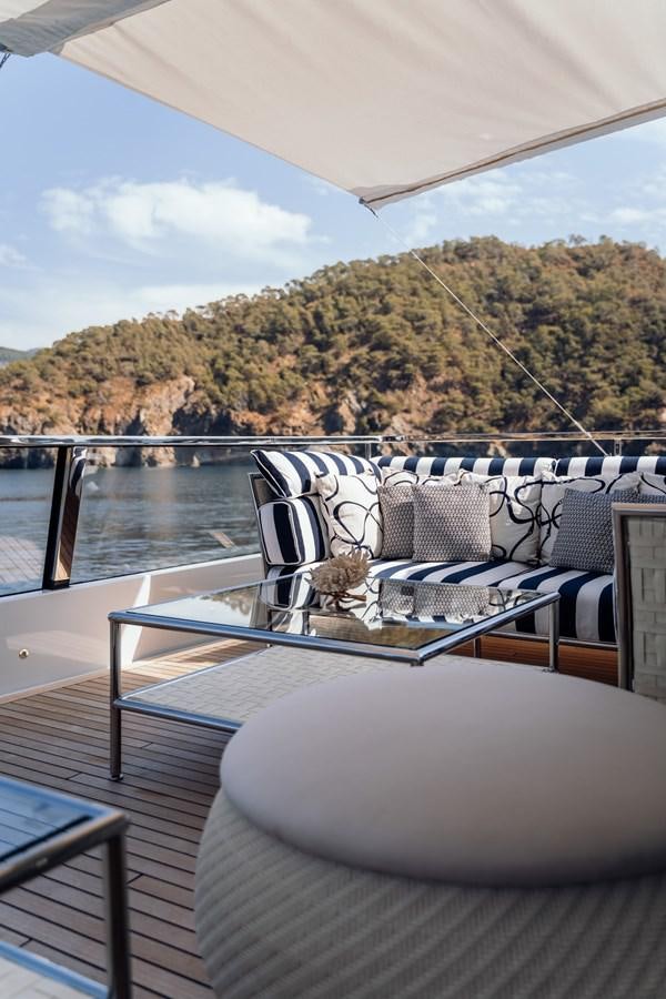 a deck with a view of a mountain and water aboard ALULIM Yacht for Sale