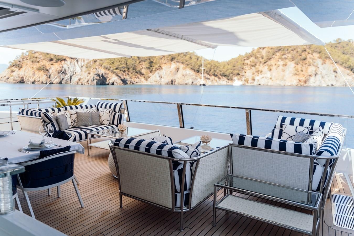 a deck with a table and chairs on it aboard ALULIM Yacht for Sale